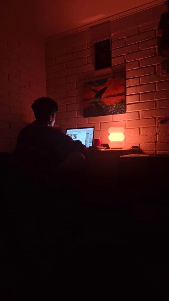 Persona trabajado en el notebook en una pieza oscura.